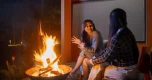 two women sitting in front of a fire pit at Bobocabin Bunaken Hills, Manado in Manado