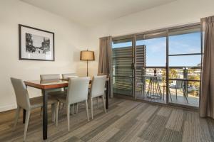a dining room with a table and chairs and a large window at Quest Melbourne Airport in Melbourne