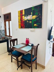 a dining room table and chairs with a painting on the wall at Neon Nirvana Deluxe Apartments in North Goa Near Calangute Candolim Anjuna in Nagoa-Bardez