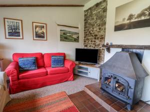 un salon avec un canapé rouge et une cheminée dans l'établissement Weathervane Cottage, à Monkton