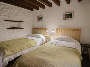 - 2 lits dans une chambre avec un mur en pierre dans l'établissement Weathervane Cottage, à Monkton