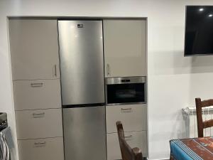 una cucina con frigorifero in acciaio inossidabile e TV di Les chambres de Marie a Didenheim
