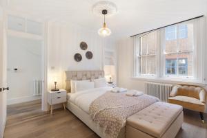 a white bedroom with a large bed and a chair at HAFH in Farringdon- Stylish 1Bedroom Apartments in London