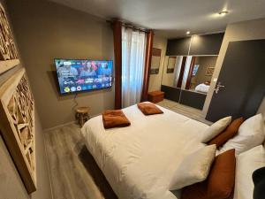 a bedroom with a large bed and a flat screen tv at L'écrin de la forêt in Jeanménil