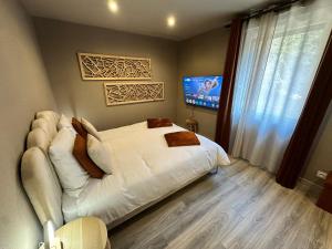 a bedroom with a white bed and a flat screen tv at L'écrin de la forêt in Jeanménil