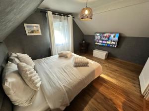 a bedroom with a white bed and a flat screen tv at L'écrin de la forêt in Jeanménil +22 photos