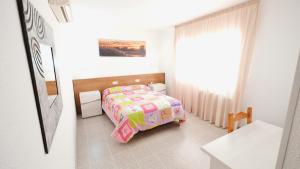 a small bedroom with a bed and a window at Hotel Paradís in Torredembarra