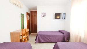 a room with a bed and a table with purple sheets at Hotel Paradís in Torredembarra