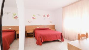 a bedroom with two beds and a red blanket at Hotel Paradís in Torredembarra
