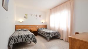 a hotel room with two beds and a window at Hotel Paradís in Torredembarra