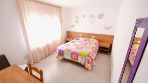 a small bedroom with a bed and a table at Hotel Paradís in Torredembarra