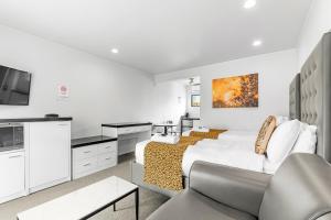 a white bedroom with a bed and a couch at Auckland Airport Motel in Auckland