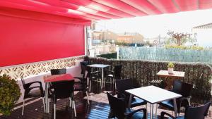 a patio with tables and chairs and a red wall at Hotel Paradís in Torredembarra