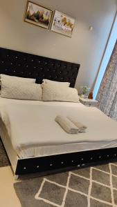 グルガオンにあるHigh-rise apartmentのベッドルーム(白い大型ベッド1台、黒いヘッドボード付)