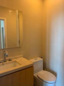 a bathroom with a toilet and a sink and a mirror at Wind Studio More than 3 nights stay in Bangkok