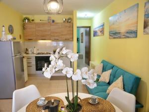 a living room with a blue couch and a table with flowers at Casa Zuliani - bilocale in Costa Azzurra in Grado