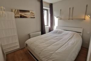 a white bed in a room with a window at Rue Bara in Roscoff