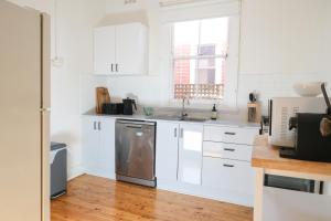 a kitchen with white cabinets and a stainless steel dishwasher at Charm and Value in Central in Wagga Wagga
