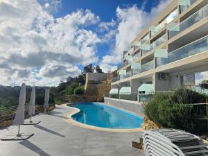 a swimming pool next to a building with chairs at Egħżien Suite A2 Access to Tranquil Shared Pool in Xagħra