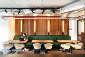 a woman sitting on a green couch in a conference room with a laptop at Coliving for Master, Postgrads and Language Learners in Barcelona +47 photos