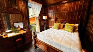 a bedroom with a bed with wooden walls and a window at Charming Nature Kampung Home for Family Getaways in Benta