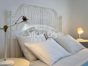 a white bed with white pillows and a lamp at Beachfront Cycladic House in Chora Folegandros