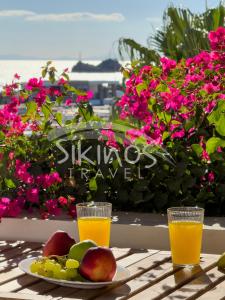a table with a plate of fruit and two glasses of orange juice at Beachfront Cycladic House in Chora Folegandros