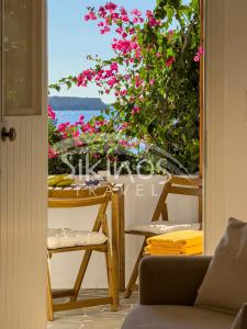 a room with a view of the ocean and pink flowers at Beachfront Cycladic House in Chora Folegandros