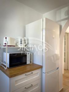 a kitchen with a microwave and a refrigerator at Beachfront Cycladic House in Chora Folegandros