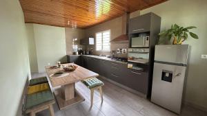 a kitchen with a table and a refrigerator at Maison Nourrit D'amour in Salazie