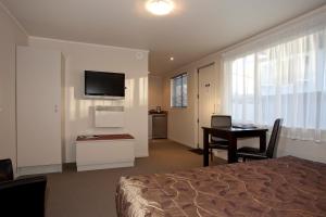 a hotel room with a bed and a desk and a television at Atrium On Ulster in Hamilton