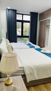 a bedroom with two beds and a table with a lamp at La La Homestay Phu Quoc in Phu Quoc