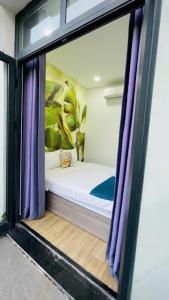 a small bed in a room with purple curtains at La La Homestay Phu Quoc in Phu Quoc