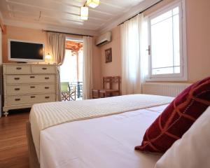 a bedroom with two beds and a dresser with a television at Achi's House in Lefkada