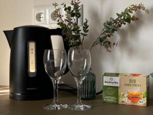 two wine glasses on a table next to a coffee maker at Appartement 105 in Egestorf