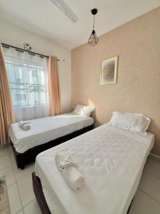 two beds in a hotel room with a window at Majestic Haven Suite in Mombasa +19 photos