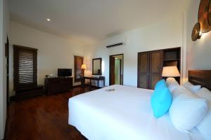 a bedroom with a large white bed with blue pillows at Ao Prao Resort in Ko Samed