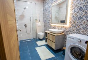 a bathroom with a shower and a sink and a washing machine at Bright & Cozy Apartment in quiet area near Airport in Golubovci