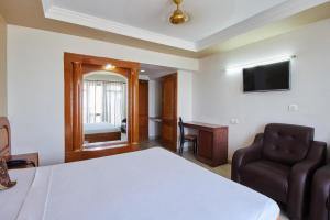 a bedroom with a bed and a chair and a television at Hotel Sun World in Kanyakumari