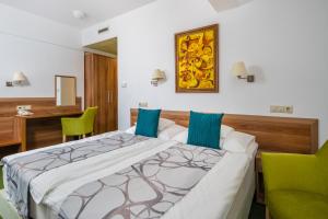 a bedroom with a large bed with two green chairs at Hotel Kiss in Tata