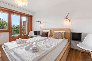 ein großes weißes Bett in einem Zimmer mit Fenstern in der Unterkunft Appartement avec terrasse, proche du centre in Crans-Montana