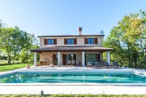 a villa with a swimming pool in front of a house at House Andrijasi in Žminj