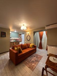 a living room with a brown couch and a kitchen at Casa de Sogno in Tbilisi City