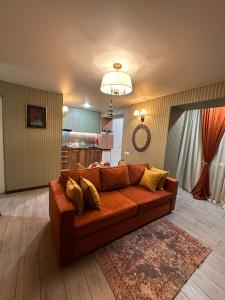 a brown couch in a living room with a kitchen at Casa de Sogno in Tbilisi City