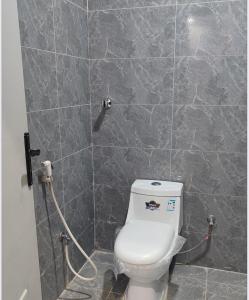 a bathroom with a toilet and a tiled wall at شقق هدى مون ليت in Al Kharj