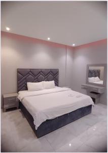 a bedroom with a large bed with white sheets at شقق هدى مون ليت in Al Kharj