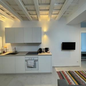 a kitchen with white cabinets and a tv on the wall at Casa Florinda Tarifa in Tarifa