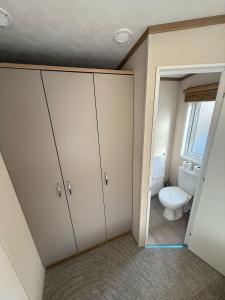 baño con aseo y armario con puerta en Goldfinch Lodge at Brickyard Lakes, en Amotherby