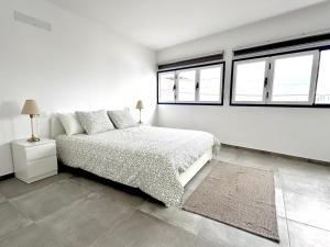 a white bedroom with a bed and two windows at Ocean View El Varadero in Punta Mujeres
