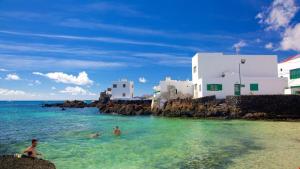 two people swimming in the ocean next to buildings at Ocean View El Varadero in Punta Mujeres